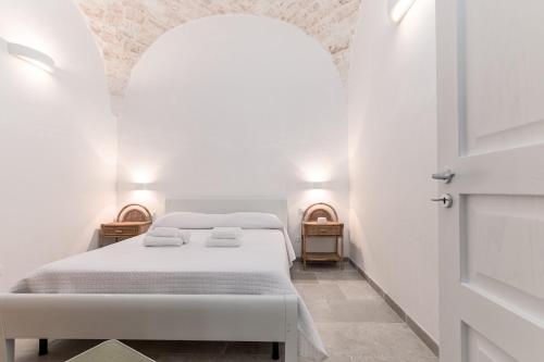 a white bedroom with a bed and two night stands at La Casetta di Chloè in Ostuni