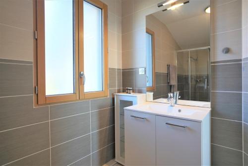 ein Badezimmer mit Waschbecken und Spiegel in der Unterkunft STUDIO dernier étage avec terrasse - vue montagne in Cruseilles