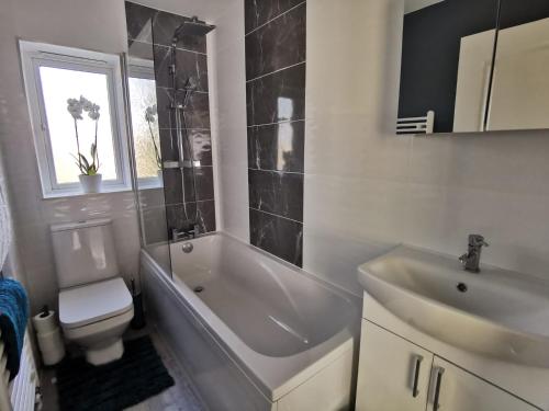 ein Badezimmer mit einer Badewanne, einem WC und einem Waschbecken in der Unterkunft Benjamin Gardens Holiday Home in Great Driffield