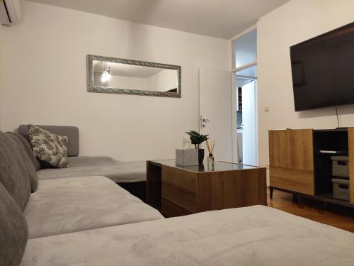 uma sala de estar com um sofá e uma televisão de ecrã plano em Apartman Ivan em Kaštela