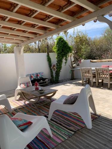 een patio met witte stoelen en een tafel op een tapijt bij Le mas des mourguettes in Saintes-Maries-de-la-Mer
