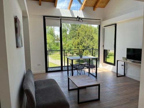 a living room with a table and chairs and a large window at El Arroyo del Sur in San Carlos de Bariloche