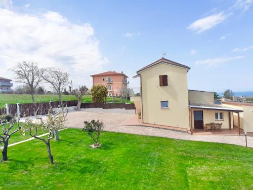 une maison avec une cour avec de l'herbe verte dans l'établissement Casa Vacanze con Vista Mare e Giardino - Amanecer, à Marzocca di Senigallia