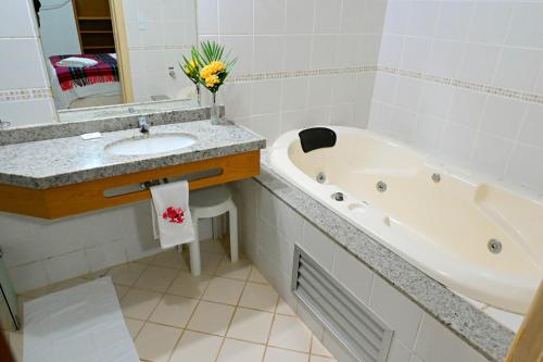 a bathroom with a sink and a bath tub at Hotel Sesi Aruana in Aruanã
