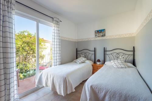 two beds in a bedroom with a large window at Apartamentos Mundaka Albir in Albir