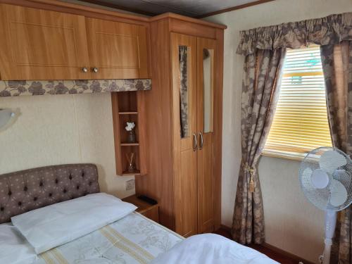 a bedroom with a bed and a window with a fan at 6 Berth central heated on Golden Sands Vintage in Ingoldmells