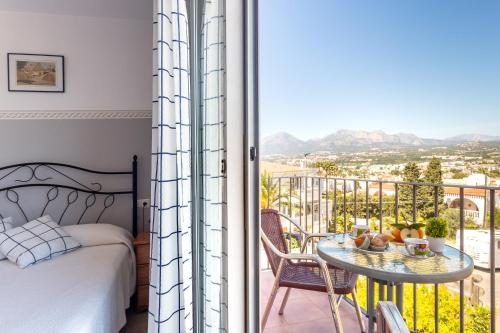 a bedroom with a bed and a balcony with a table at Apartamentos Mundaka Albir in Albir