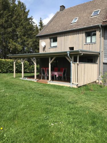 una casa con un porche con sillas rojas. en Ferienhaus Michels, en Hellenthal