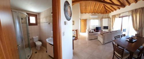 a bathroom with a toilet a sink and a living room at Stathi's House in Megali Ammos