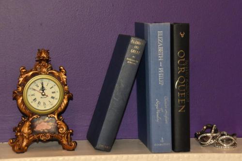 tre libri seduti accanto ad un orologio su uno scaffale di Seabank House Bed and Breakfast The Royal a Pictou