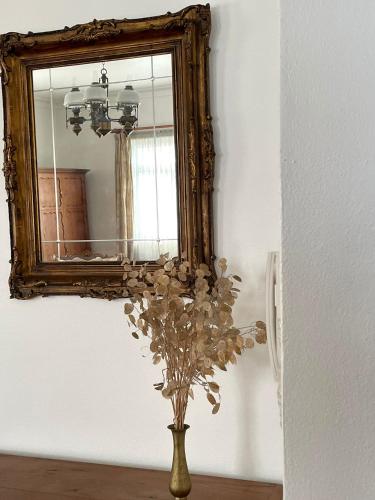 a vase with flowers in front of a mirror at Casa Às Oito in Angra do Heroísmo