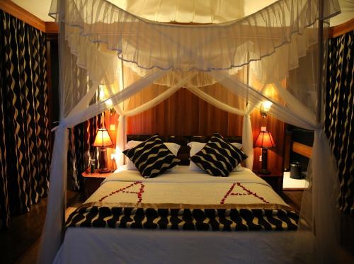 a bedroom with a canopy bed with black and white pillows at AA Lodge Maasai Mara in Talek