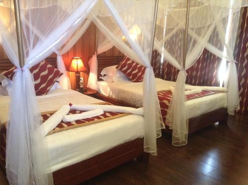two beds in a bedroom with drapes at AA Lodge Maasai Mara in Talek