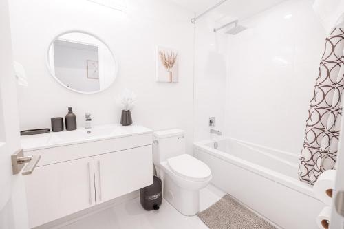 a white bathroom with a toilet and a sink and a tub at Luxury & Comfy Apartment, Mins Drive To All Niagara Falls Attraction in Niagara Falls