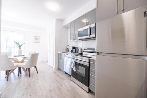 a kitchen with a refrigerator and a table with chairs at Luxury & Comfy Apartment, Mins Drive To All Niagara Falls Attraction in Niagara Falls