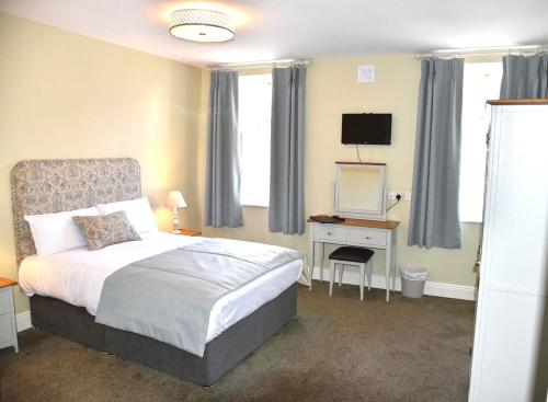 a bedroom with a bed and a desk with a television at Befani's Mediterranean Restaurant & Townhouse in Clonmel