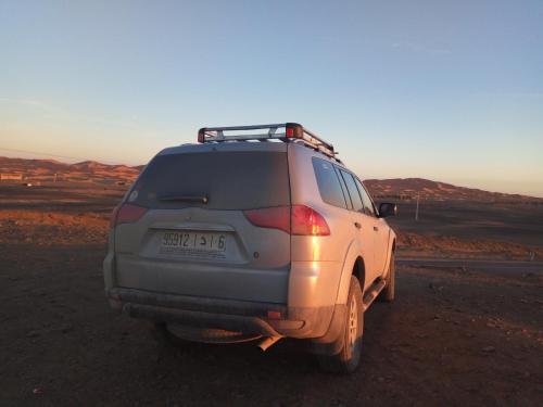 a suv parked on the side of a road at Sahara Desert Camp in Adrouine