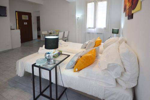 a white bed with pillows and a table with a lamp at 4-Tourist House Bologna-Studio - Self check-in in Bologna