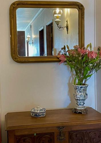 a vase of flowers on a table in front of a mirror at Casa Às Nove in Angra do Heroísmo