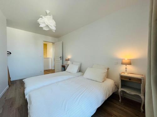 - une chambre avec un lit blanc et une table de chevet avec une lampe dans l'établissement La Casa D'Alauna, à Valognes