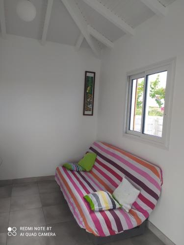 a striped couch in a room with a window at Location vacances Guadeloupe Gite et table d'hôtes Kaz a Klemence Anse-Bertrand in Anse-Bertrand