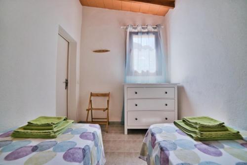 a bedroom with two beds and a dresser and a window at Casa Abeja in Colonia de Sant Pere