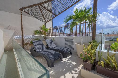 un patio con 2 sillas y palmeras en un balcón en Aruma Suites, en Playa del Carmen