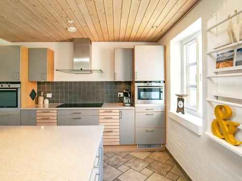 Hurupにある12 person holiday home in Hurup Thyの白いキャビネットと木製の天井が備わるキッチン