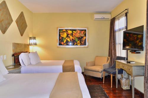 a hotel room with two beds and a flat screen tv at Hotel Mesones 49 in San Miguel de Allende