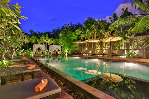 a pool with chairs and umbrellas at night at Home Indochine D'angkor Hotel in Siem Reap