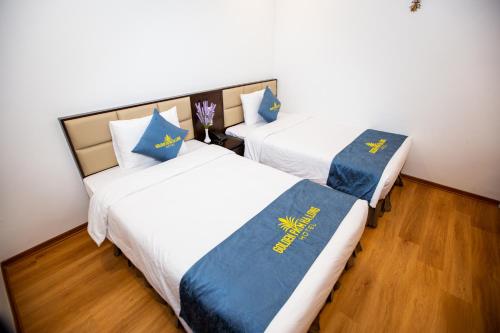 a bedroom with two beds with blue and yellow pillows at Golden Palm HaLong Hotel in Ha Long