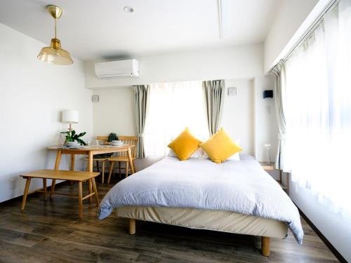 a bedroom with a bed with yellow pillows and a table at City Hideout in Tokyo