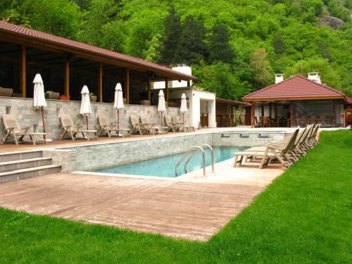 einen Pool mit Stühlen und Sonnenschirmen neben einem Haus in der Unterkunft Aqua Varvara Hotel in Varvara