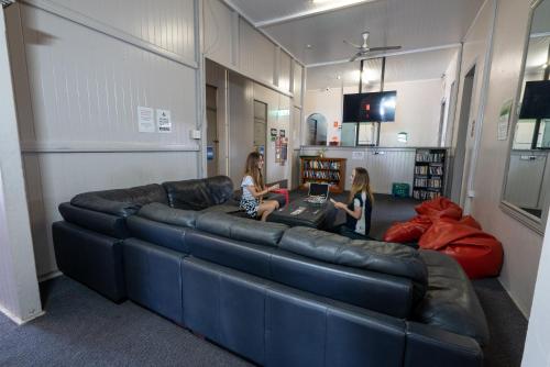 two girls sitting on a leather couch in a room at The Jack Backpackers in Cairns
