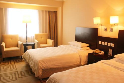 a hotel room with two beds and two chairs at Beijing Continental Grand Hotel in Beijing
