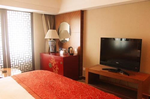 a hotel room with a bed and a flat screen tv at Beijing Continental Grand Hotel in Beijing