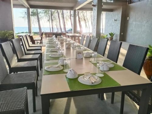 una mesa larga con platos y servilletas. en The Chevalley Beach Resort en Satun