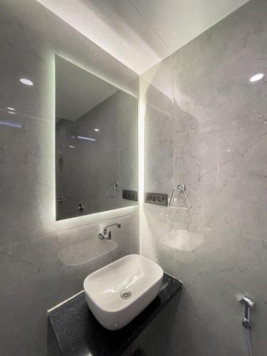 a white bathroom with a sink and a mirror at Regency Farm House With Pvt Swimming Pool Surat in Surat