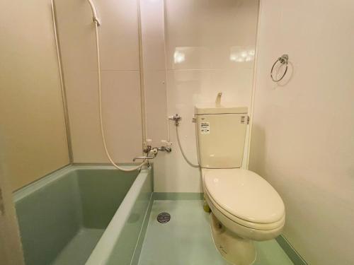 a bathroom with a toilet and a bath tub at サービスアパ―トメントSAPPORO札幌さくら2-3 in Sapporo