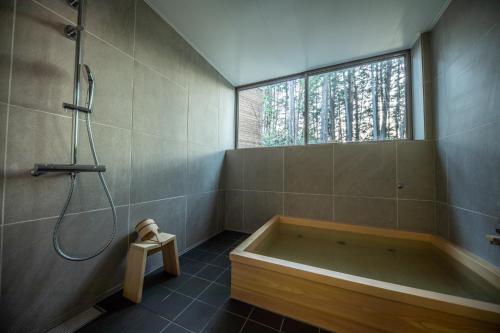 a bathroom with a bath tub and a window at Auberge Hidanomori in Takayama