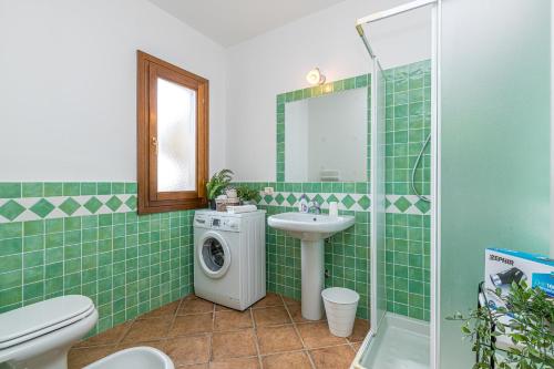 a green tiled bathroom with a sink and a washing machine at Le Dimore di Nettuno in Olbia