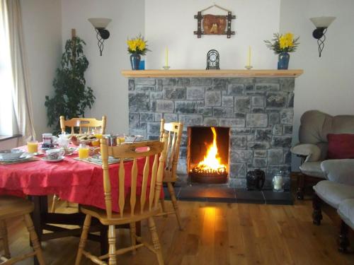 uma sala de estar com uma mesa e uma lareira em Mountainview B&B em Leenaun