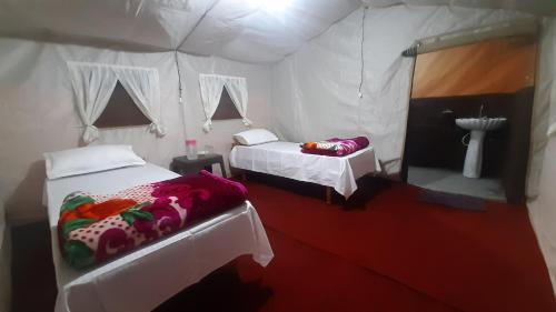 um quarto com duas camas numa tenda branca em The Harsil Stay em Harsil