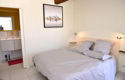 1 dormitorio con 1 cama con sábanas y almohadas blancas en Les Chambres de Montplaisir, en Marsillargues