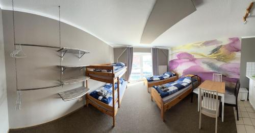 Zimmer mit 3 Etagenbetten, einem Tisch und einem Esszimmer in der Unterkunft Hostel Fehmarn Ferienwohnung in Fehmarn