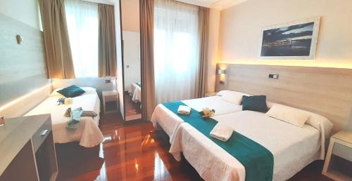 a hotel room with two beds and a table at Hotel Nueva Plaza in Maliaño