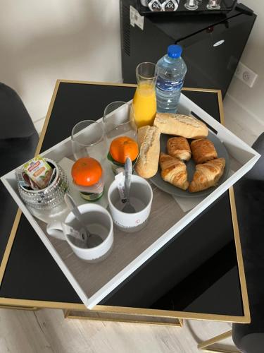 a tray of food with bread and oranges on a table at Gîte avec piscine in Lestrem