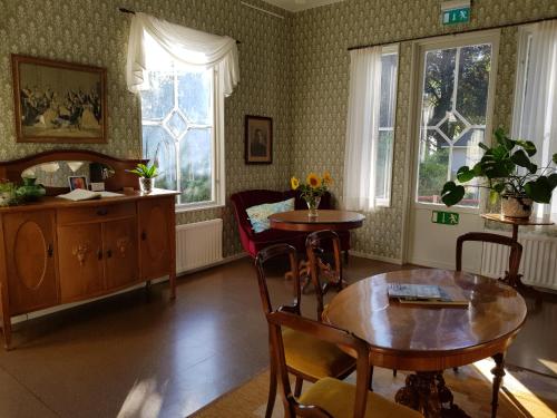 - un salon avec une table, des chaises et des fenêtres dans l'établissement Villa Eira vandrarhem, à Hjo