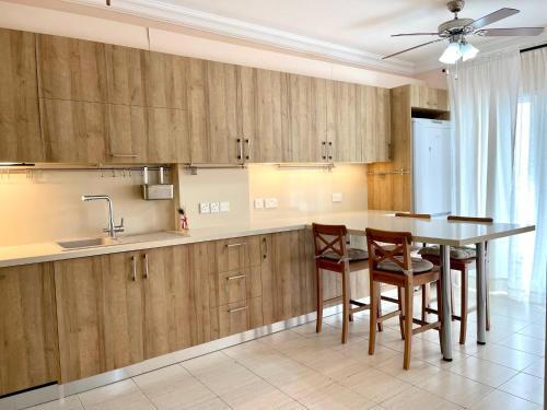 a kitchen with wooden cabinets and a table and chairs at 100 m to the beach Sea La Vie 3 bedroom Apartment in Limassol