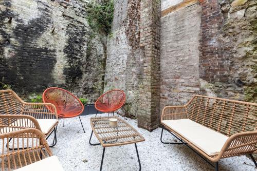 L'Atelier d'Eléa - 4 - Terrace - Indus-chic in the heart of Honfleur - 6 P في أونفلور: مجموعة من الكراسي والطاولات بجانب جدار من الطوب